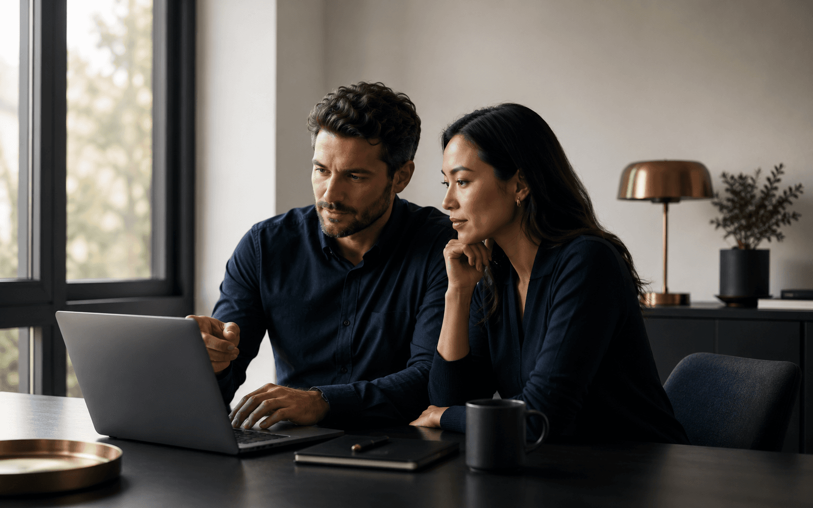 Two colleagues reviewing work together on a laptop.